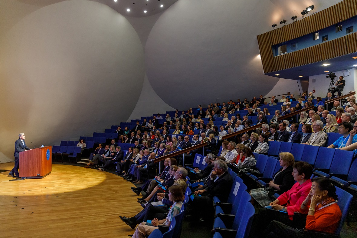 Φωτογραφία από ένα αμφιθέατρο στο οποίο ο κόσμος κάθεται και παρακολουθεί τον άντρα που είναι στο βήμα και μιλά