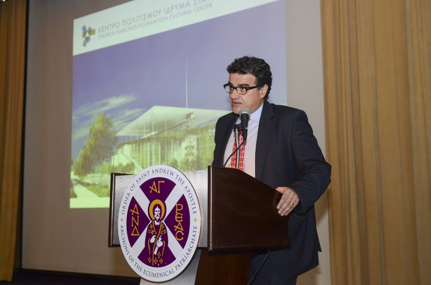 Ένας άντρας μιλάει στο βήμα του Οικουμενικού Πατριαρχίου και δίπλα του προβάλλεται μια φωτογραφία από το κτήριο του Ιδρύματος Σταύρος Νιάρχος