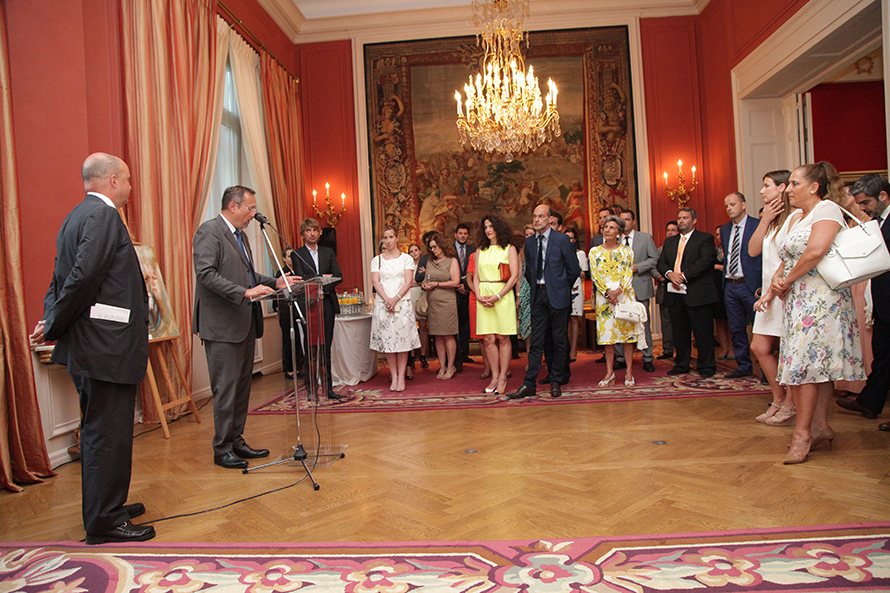 Ο Ανδρέας Δρακόπουλος, πρόεδρος του Ιδρύματος Σταύρος Νιάρχος, στέκεται δίπλα σε έναν άνδρα που δίνει ομιλία πίσω από ένα βήμα μπροστά σε όρθιο κοινό.