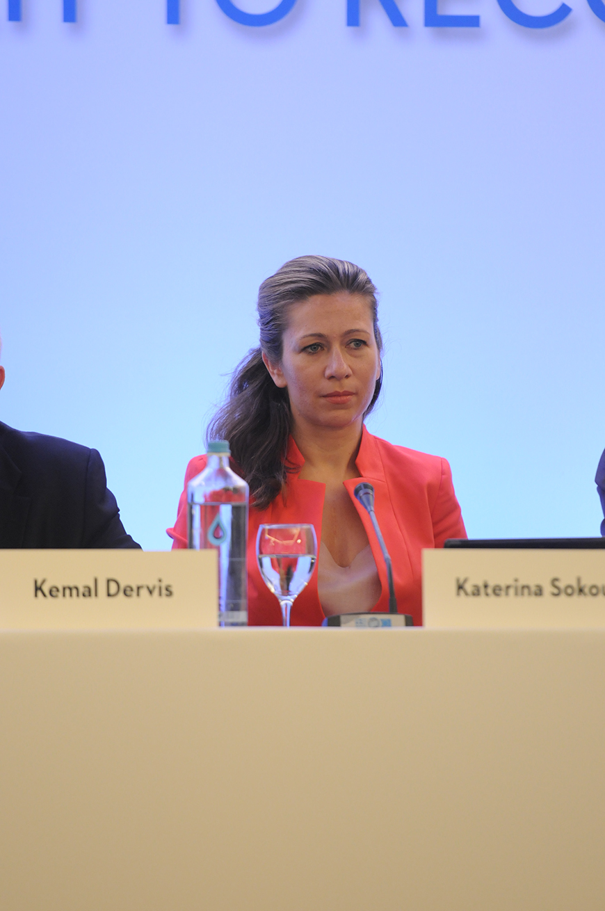 Κοντινή φωτογραφία μιας γυναίκας η οποία κάθεται σε ένα τραπέζι και έχει μπροστά της ένα μικρόφωνο