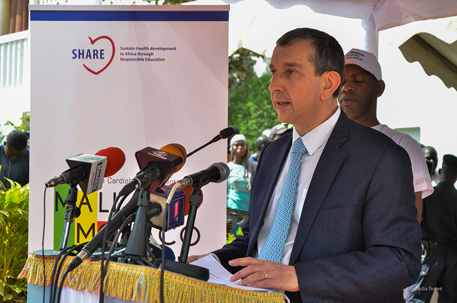 Ένας άντρας μιλάει στο βήμα ενώ δίπλα του υπάρχει ένα banner το οποίο γράφει 