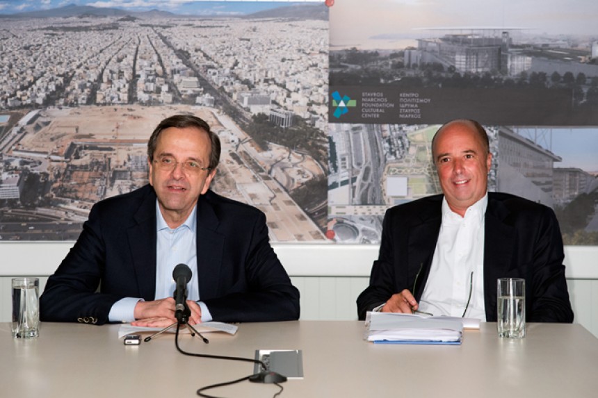 Ο Αντώνης Σαμαράς, πρωθυπουργός της Ελληνικής Δημοκρατίας, και ο Ανδρέας Δρακόπουλος, πρόεδρος του Ιδρύματος Σταύρος Νιάρχος, κάθονται σε ένα τραπέζι μπροστά από μια εικόνα του εργοταξίου του Κέντρου Πολιτισμού του Ιδρύματος Σταύρος Νιάρχος