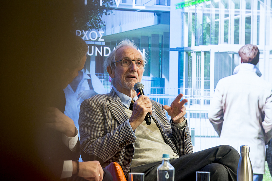 Κοντινή φωτογραφία ενός άντρα που κάθεται στη σκηγή και μιλάει κρατώντας ένα μικρόφωνο