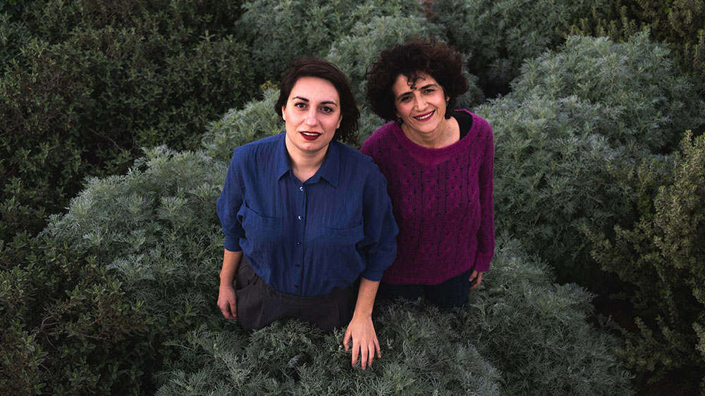 Δύο γυναίκες στέκονται στη μέση ενός πράσινου χωραφιού