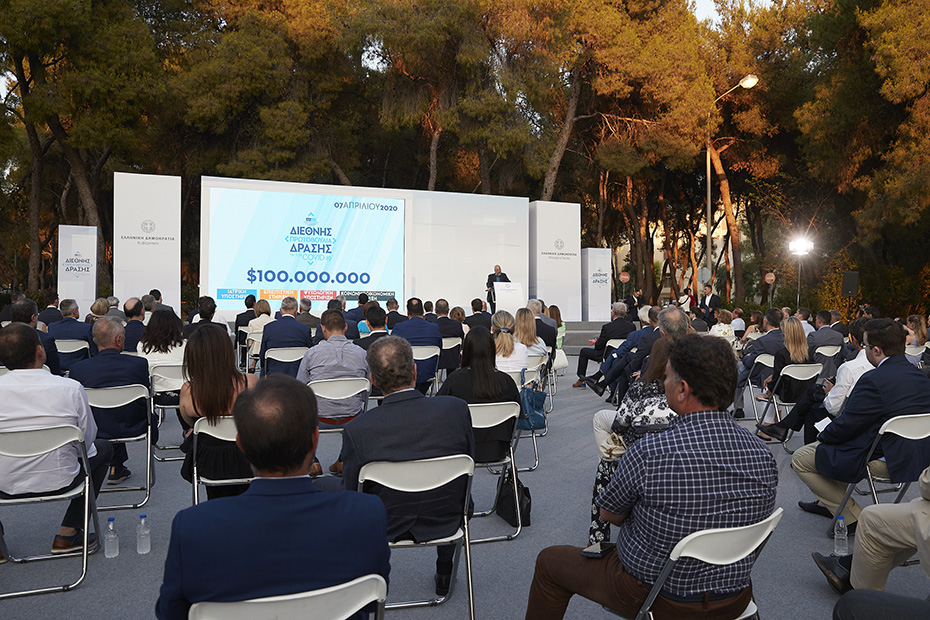 Φωτογραφία που δείχνει πλήθος ανθρώπων να κάθεται σε καρέκλες τοποθετημένες σε εξωτερικό χώρο και να παρακολουθεί μια ομιλία 