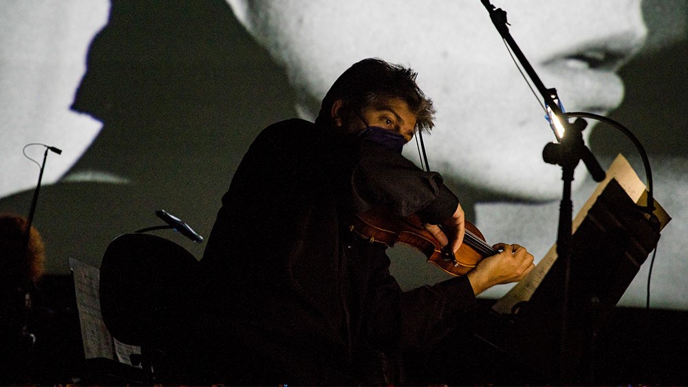 Ένας μουσικός παίζει βιολί και κοιτάει τις παρτιτούρες του 