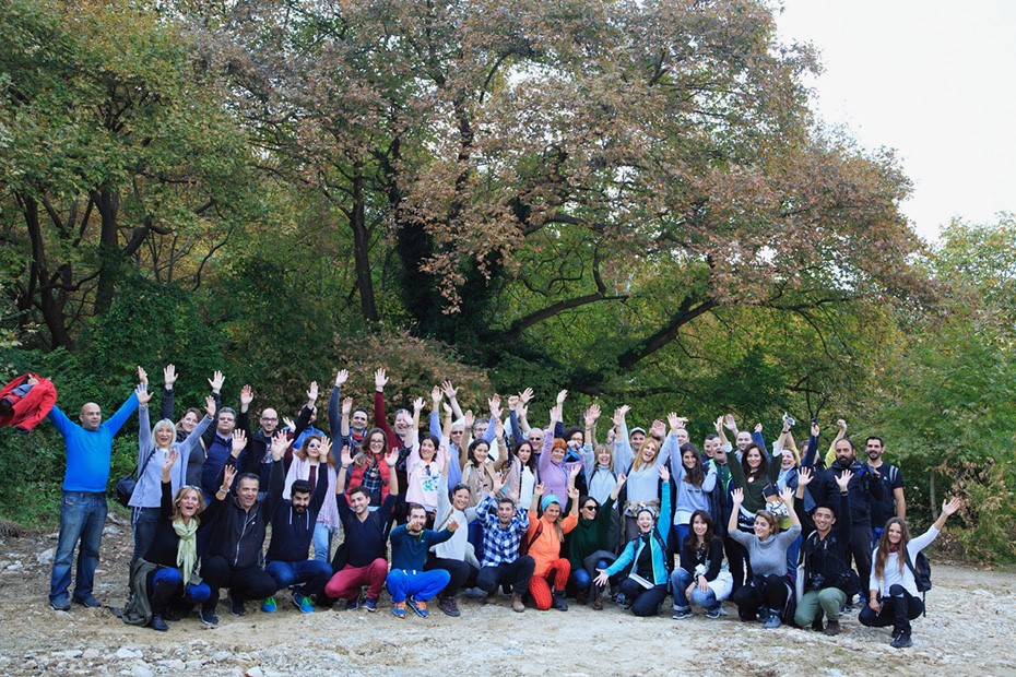 Πλήθος ανθρώπων σηκώνει τα χέρια ψηλά και χαμογελάει για μια αναμνηστική φωτογραφία σε ένα μονοπάτι στο δάσος