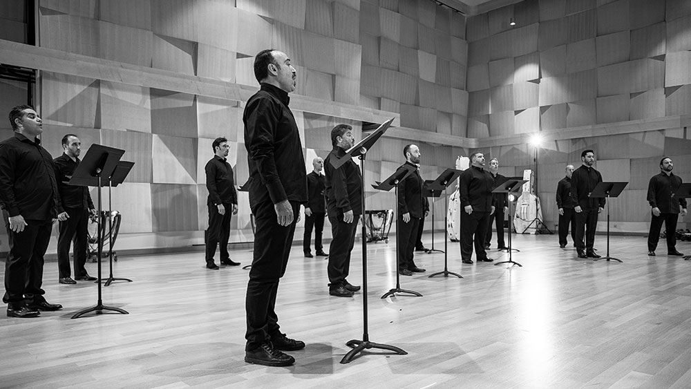 Μια ανδρική χορωδία τραγουδάει σε μια μεγάλη αίθουσα