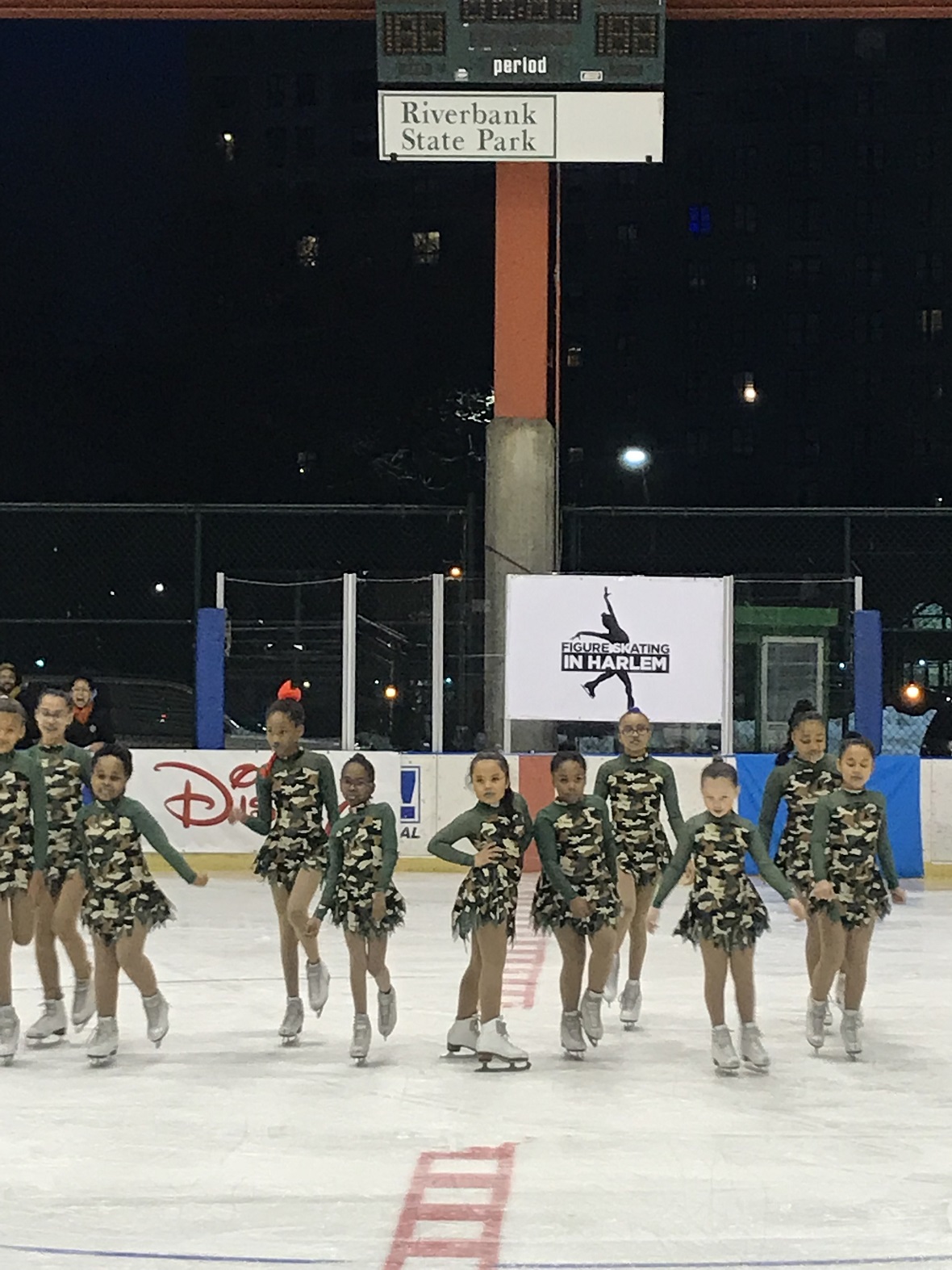 Μια ομάδα κοριτσιών με ασορτί κοστούμια κάνουν πατινάζ σε παγοδρόμιο