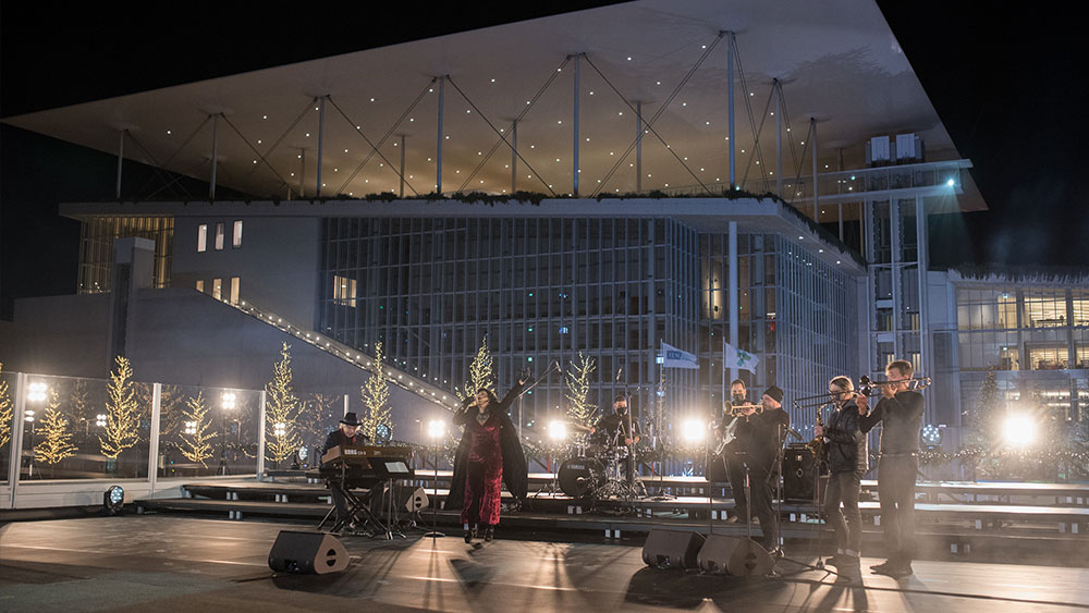 Μια γυναίκα τραγουδά, συνοδευόμενη από μπάντα, έξω από το Κέντρο Πολιτισμού Ίδρυμα Σταύρος Νιάρχος