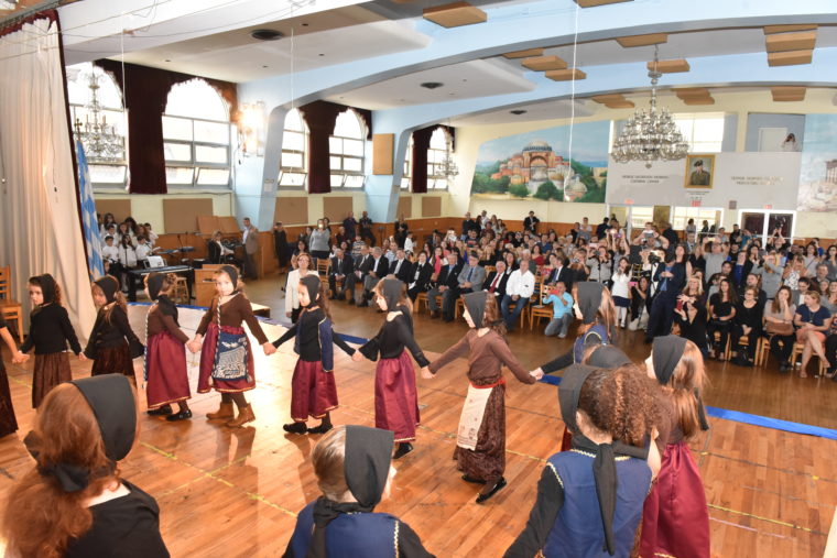 Μικρά κορίτσια φοράνε παραδοσιακές στολές και χορεύουν σε κύκλο ελληνικό παραδοσιακό χορό 