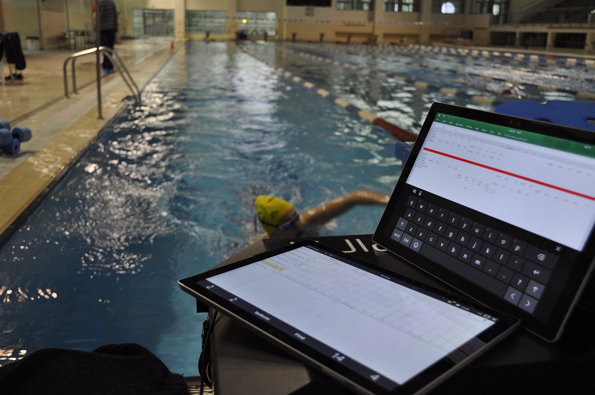Φωτογραφία που δείχνει μια αθλήτρια κολύμβησης στο νερό και δύο tablets μετρούν τις επιδόσεις της 