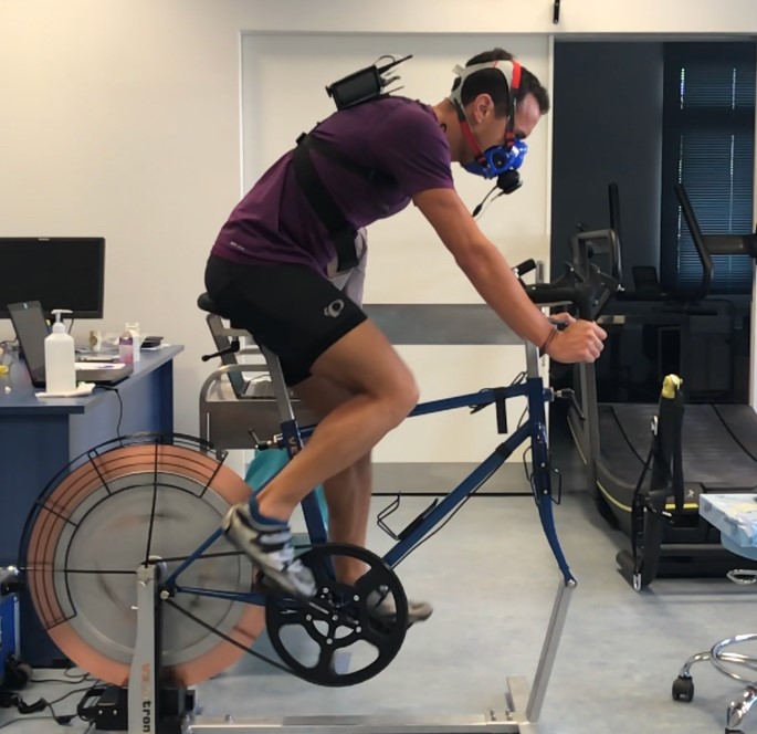 Ένας άντρας φοράει ειδική μάσκα οξυγόνου και κάνει στατικό ποδήλατο σε ένα εργαστήριο γυμναστικής 