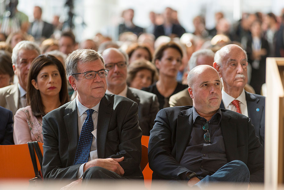 Ο Ανδρέας Δρακόπουλος, πρόεδρος του Ιδρύματος Σταύρος Νιάρχος, κάθεται δίπλα σε έναν άνδρα και παρακολουθούν με προσοχή την παρουσίαση