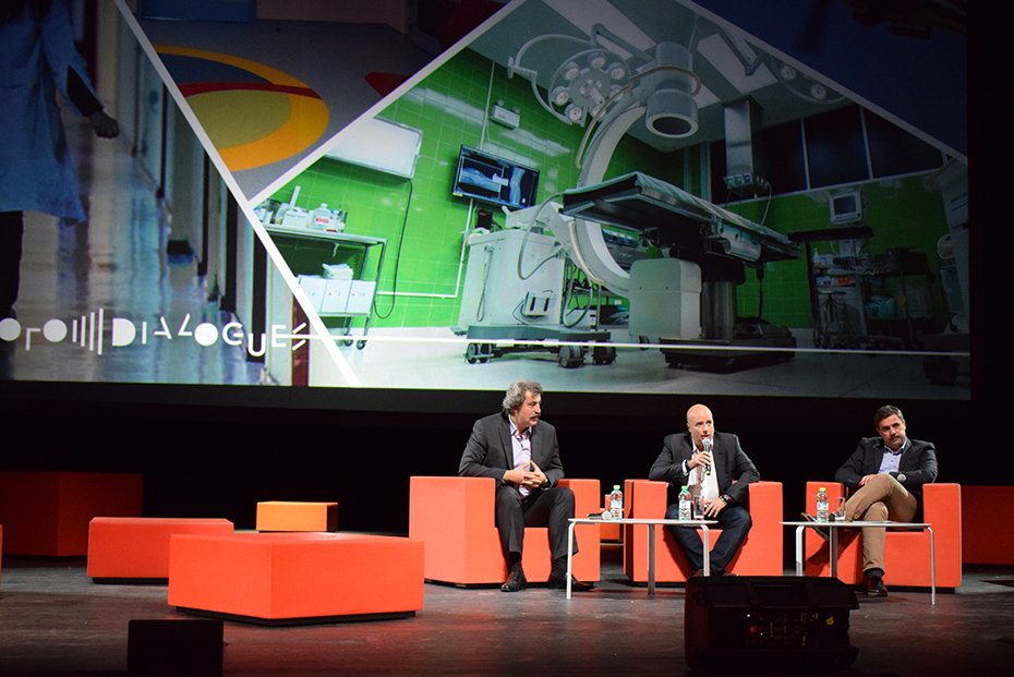 Ο Ανδρέας Δρακόπουλος, πρόεδρος του Ιδρύματος Σταύρος Νιάρχος, κάθεται στη σκηνή μαζί με άλλους δύο άνδρες και μιλάει στο πλαίσιο των Διαλόγων του Ιδρύματος Σταύρος Νιάρχος