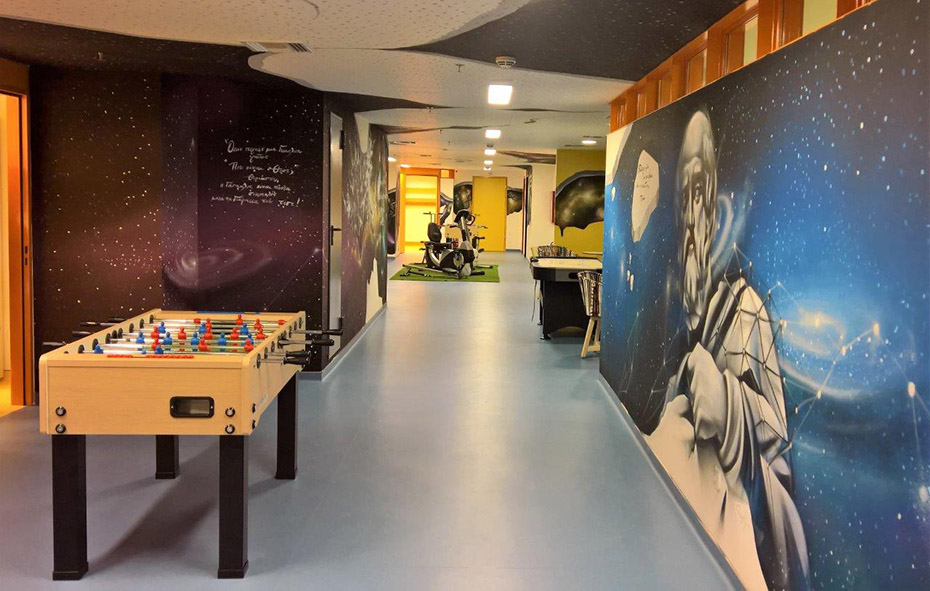 Φωτογραφία ενός διαδρόμου στον οποίο υπάρχει ένα ποδοσφαιράκι και ο ένας τοίχος είναι ζωγραφισμένος με έναν ήρωα παιδικής σειράς 