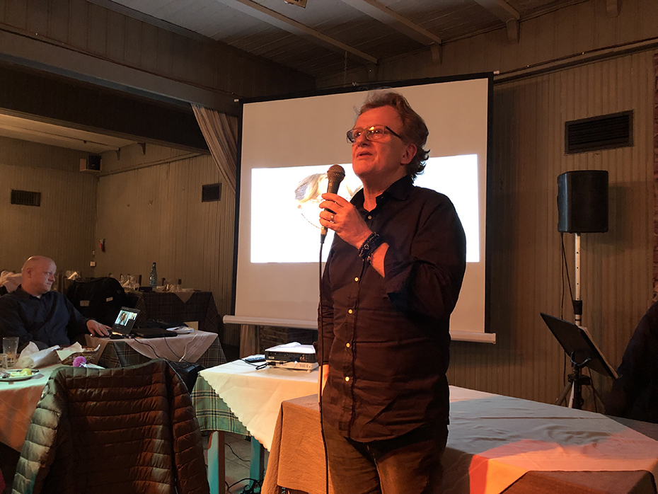 Ένας άντρας στέκεται όρθιος, κρατάει ένα μικρόφωνο και μιλάει 