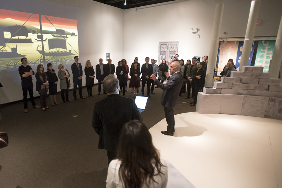 Ένας άνδρας μιλάει σε συγκεντρωμένο πλήθος σε ένα μουσείο