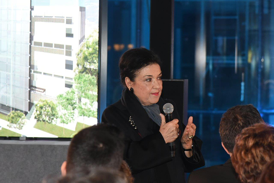 Κοντινή φωτογραφία μιας γυκαίακας η οποία στέκεται όρθια στη σκηνή και μιλάει στο μικρόφωνο 