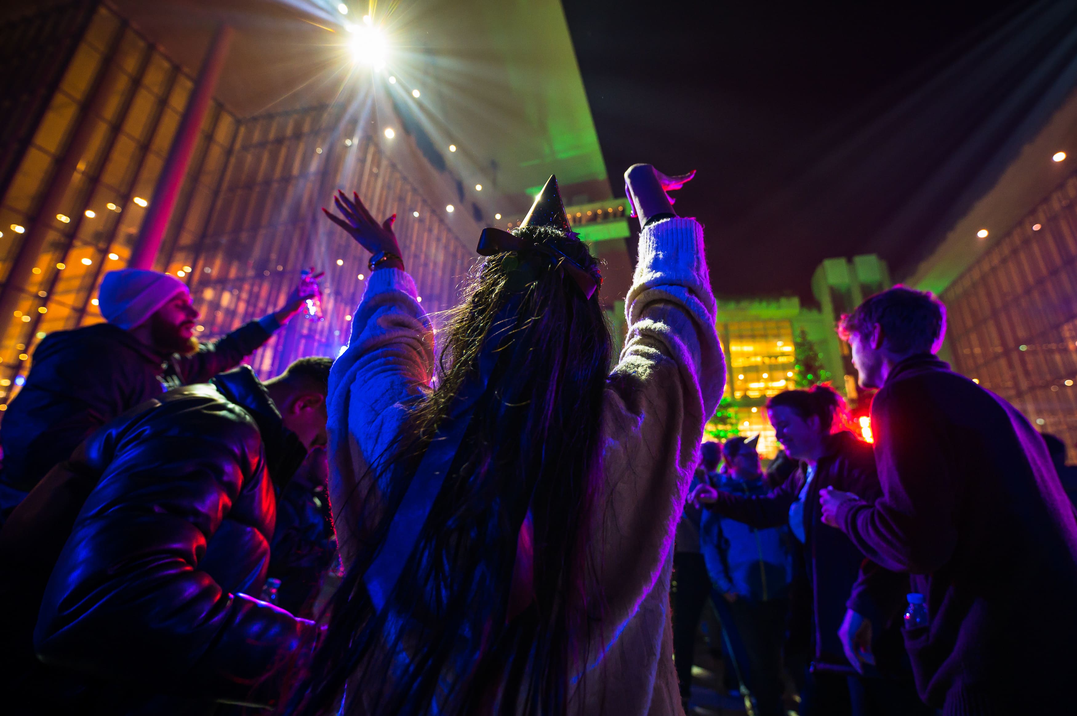 Άτομα φωτισμένα με έντονα χρώματα που χορεύουν στην Αγορά του ΚΠΙΣΝ.