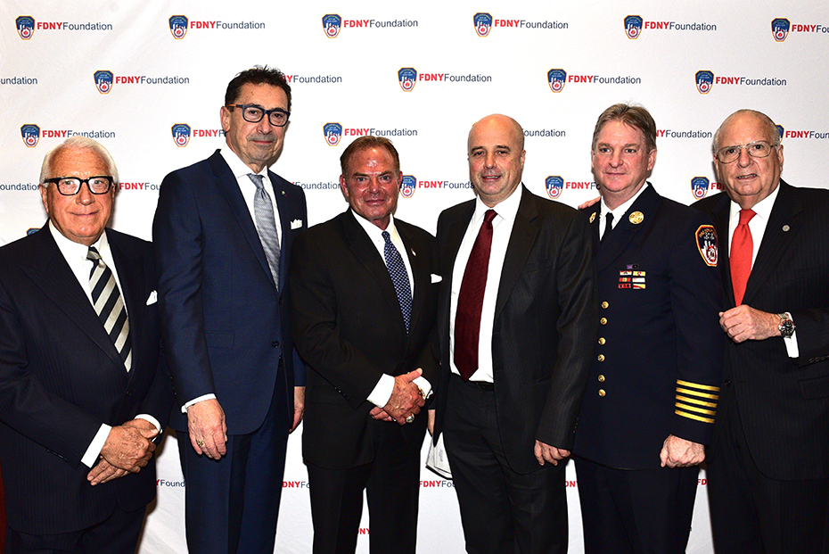 Ο Αντρέας Δρακόπουλος, Πρόεδρος του Ιδρύματος Σταύρος Νιάρχος, στέκεται μαζί με άλλους τέσσερις άντρες και φωτογραφίζεται μπροστά από ένα banner που γράφει FDNY FOUNDATION
