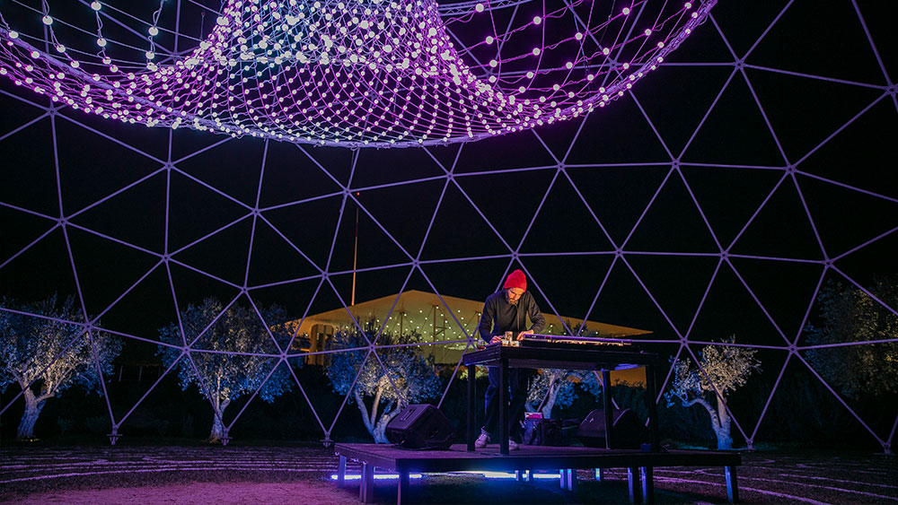 Ένας άνδρας μέσα σε μια εντυπωσιακή ημικυκλική φωτιστική κατασκευή έξω από το Κέντρο Πολιτισμού Ίδρυμα Σταύρος Νιάρχος