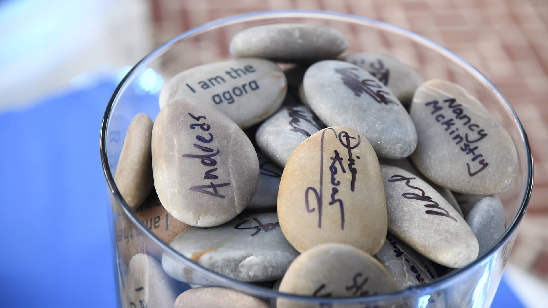 Ένα βάζο γεμάτο μικρές πέτρες στις οποίες έχουν γραφτεί διάφορα ονόματα 