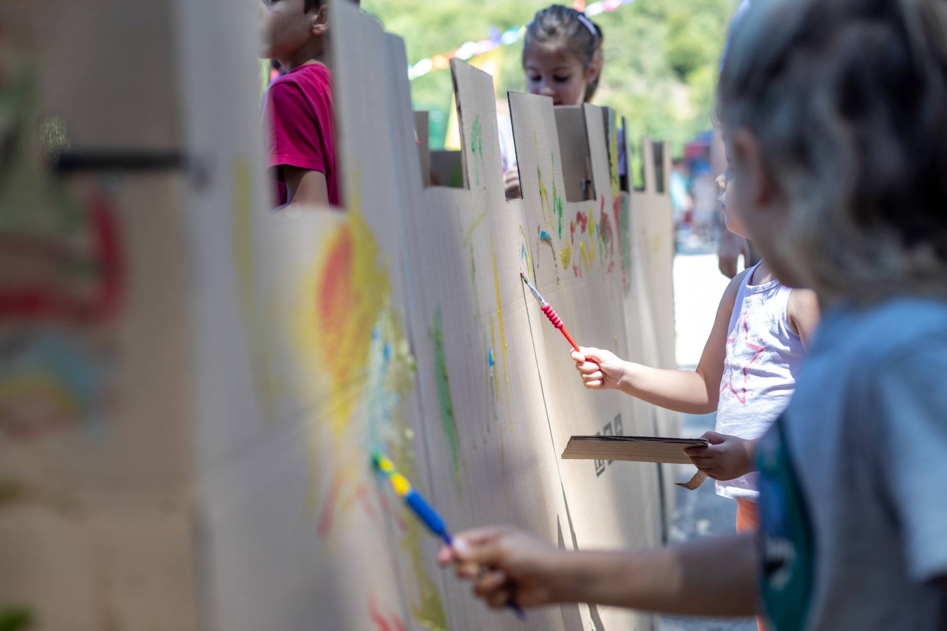 Παιδία κρατούν πινέλα και ζωγραφίζουν σε καμβάδες.