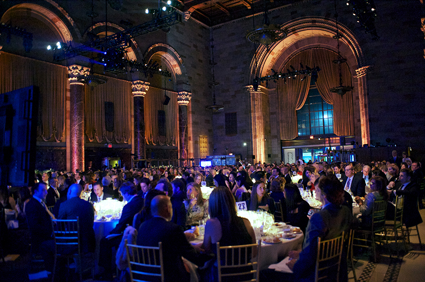 Φωτογραφία που δείχνει κόσμο να κάθεται σε στρογγυλά τραπέζια κατά τη διάρκεια μιας δεξίωσης