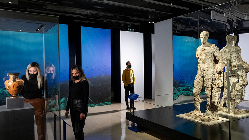 Δύο άνθρωποι κοιτούν αρχαιοελληνικά εκθέματα 