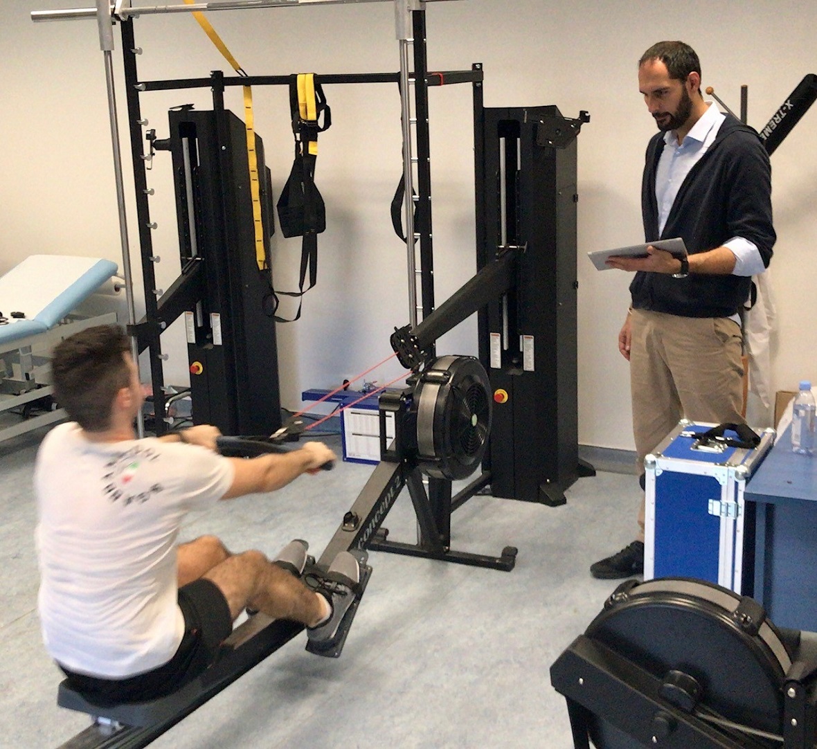 Ένας αθλητής χρησιμοποιεί ένα όργανο γυμναστικής και ο ειδικός τον παρακολουθεί 