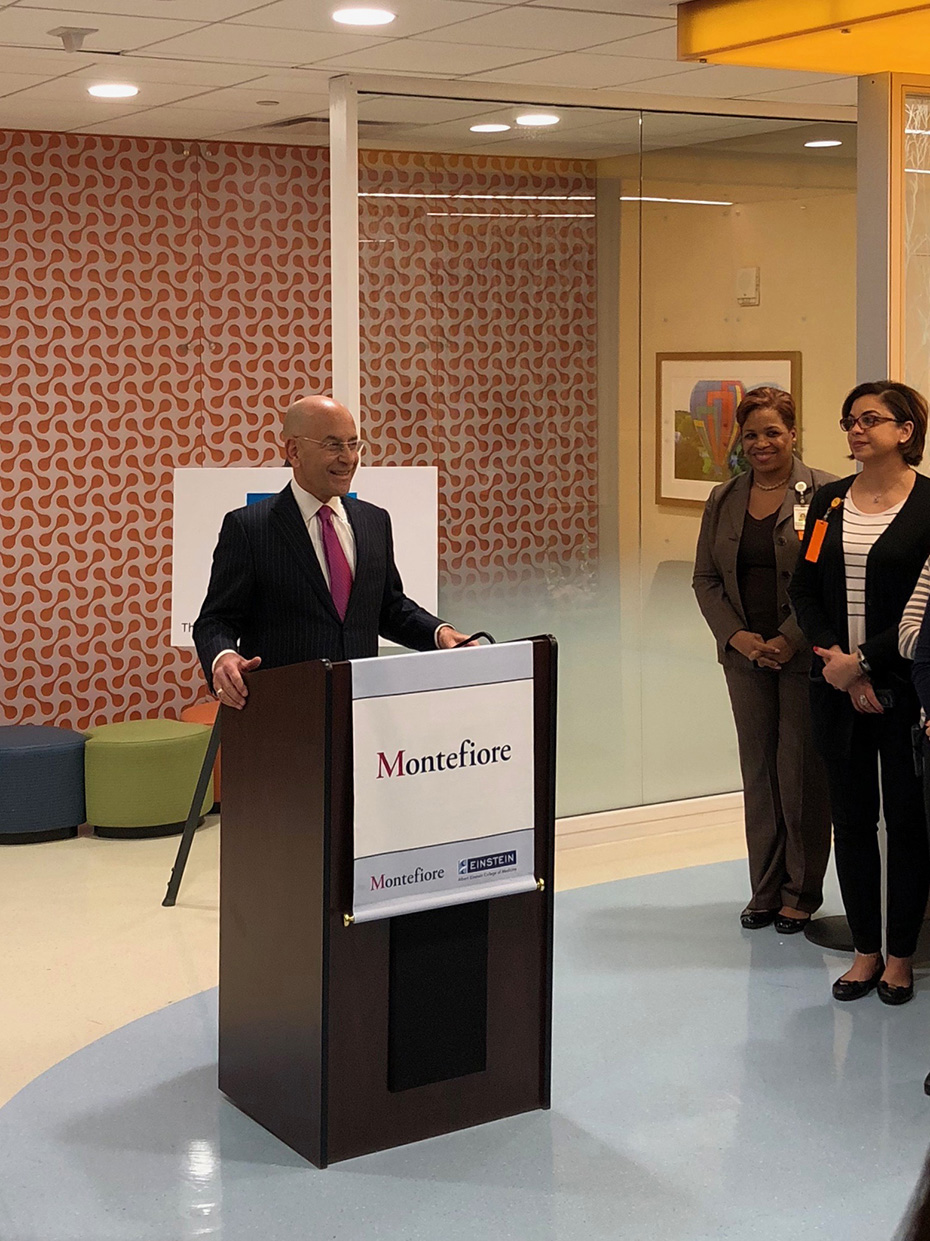 Ένα μέλος του Ιατρικού Κέντρου Montefiore δίνει ομιλία και χαμογελάει ενώ ο κόσμος γύρω του τον ακούει