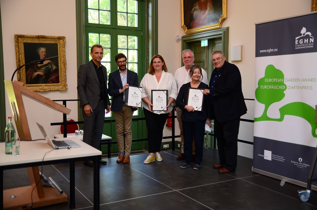 Δύο γυναίκες και τέσσερις άντρες στέκονται κρατώντας επαίνους και χαμογελούν για μια φωτογραφία 