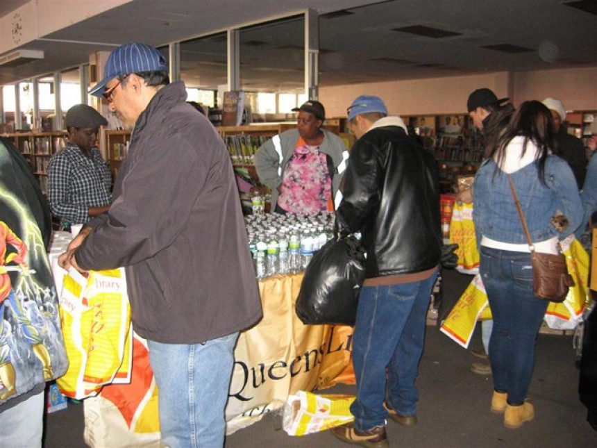 Άνθρωποι κρατάνε στα χέρια τους σακούλες και από πάγκους τις γεμίζουν με μπουκάλια νερού και τρόφιμα