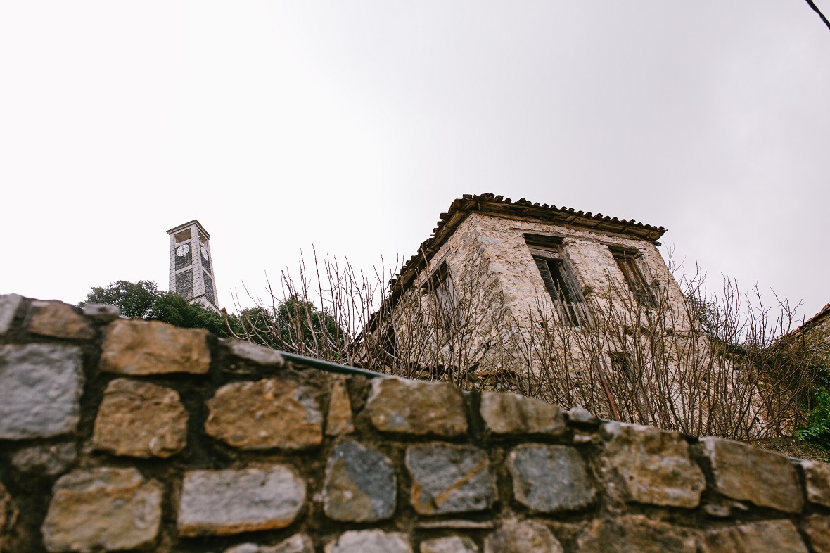 Φωτογραφία τραβηγμένη από κάτω προς τα πάνω η οποία δείχνει ένα πέτρινο σπίτι πάνω σε ένα πέτρινο ύψωμα