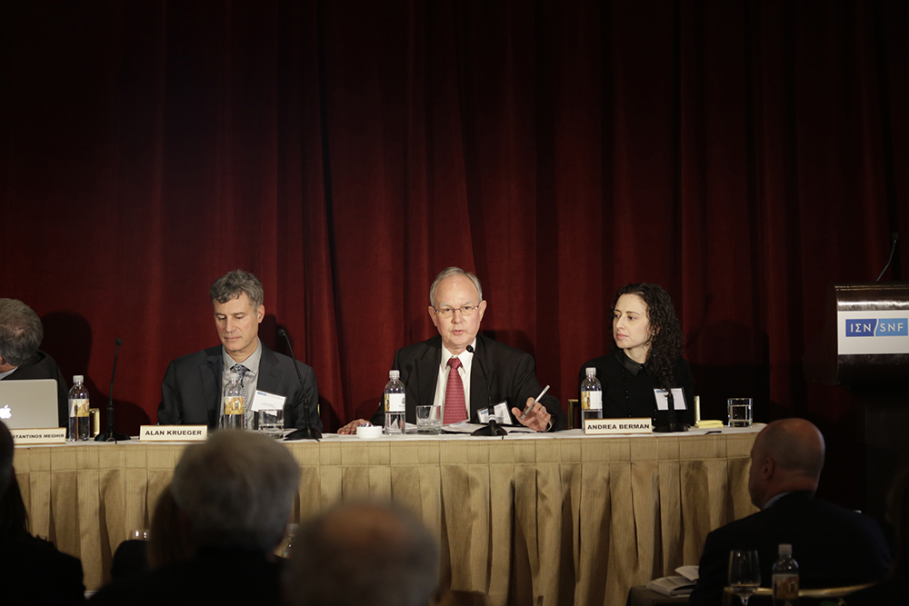 Τρεις εκπρόσωποι του συνεδρίου κάθονται σε ένα τραπέζι μπροστά στο κοινό