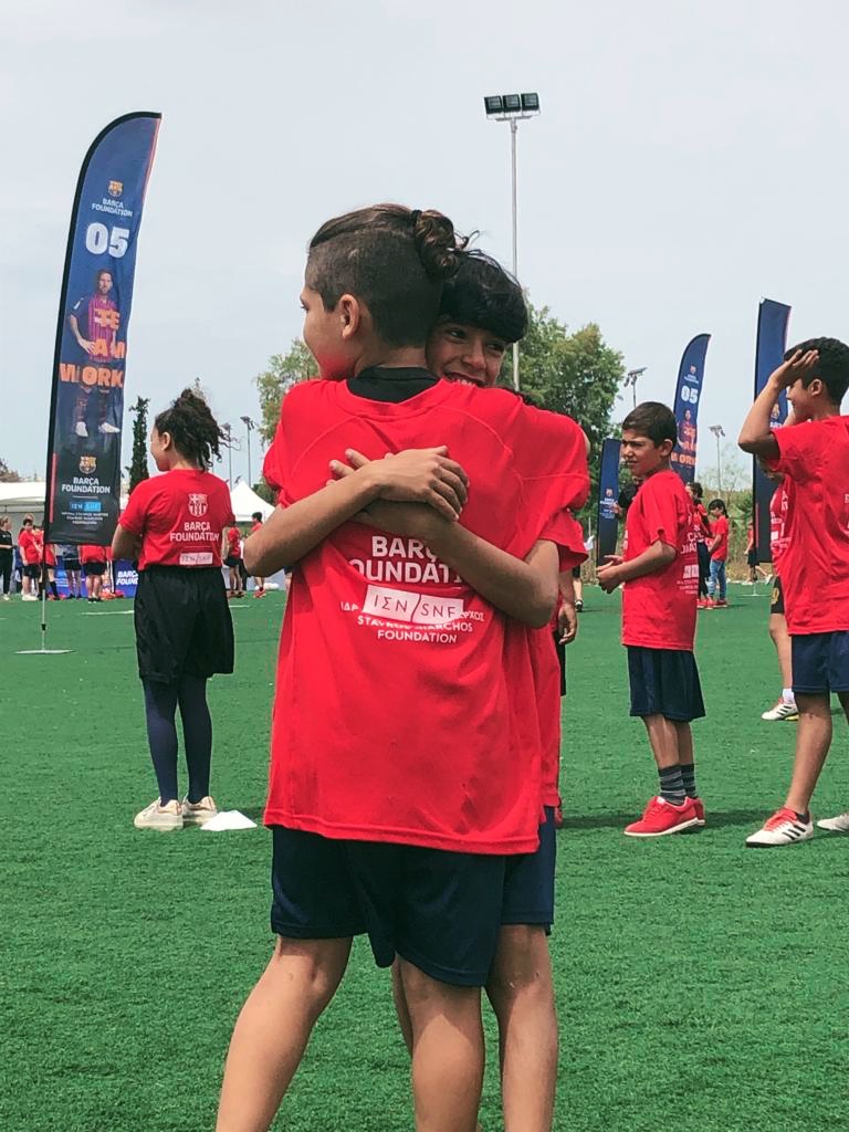 Δύο παιδιά της ίδιας ομάδας αγκαλιάζονται στο γήπεδο ποδοσφαίρου