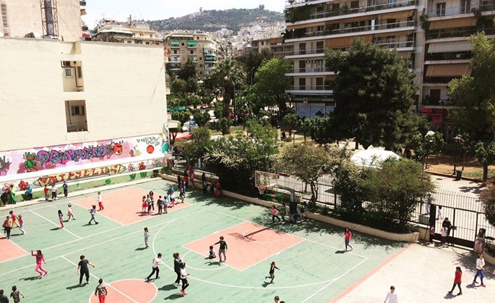 Φωτογραφία τραβηγμένη από ψηλά η οποία δείχνει τα γήπεδα μπάσκετ ενός σχολείου να είναι γεμάτα από παιδιά που παίζουν