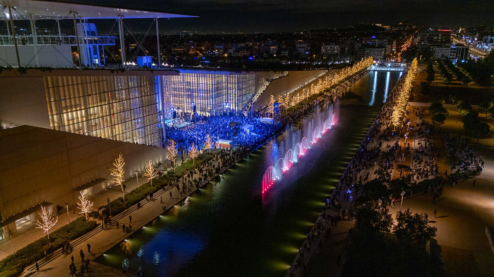 Αεροφωτογραφία του ΚΠΙΣΝ φωτισμένο από χριστουγεννιάτικα φώτα και χορογραφημένα σιντριβάνια.