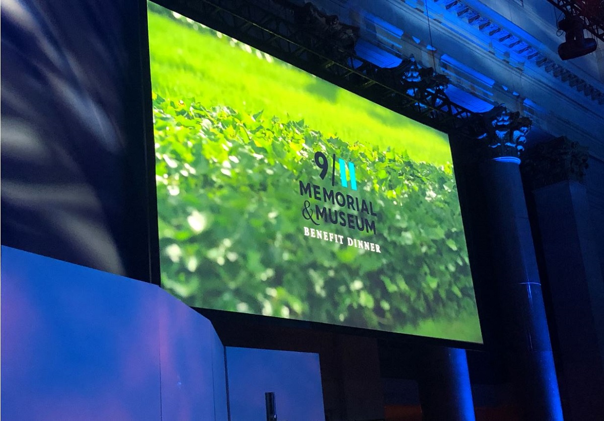 A screen which has a green grass-like background and reads 9 I II Memorial & Museum BENEFIT DINNER