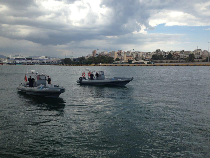 Πέντε μέλη της Ελληνικής Ακτοφυλακής στέκονται σε δύο βάρκες στη θάλασσα