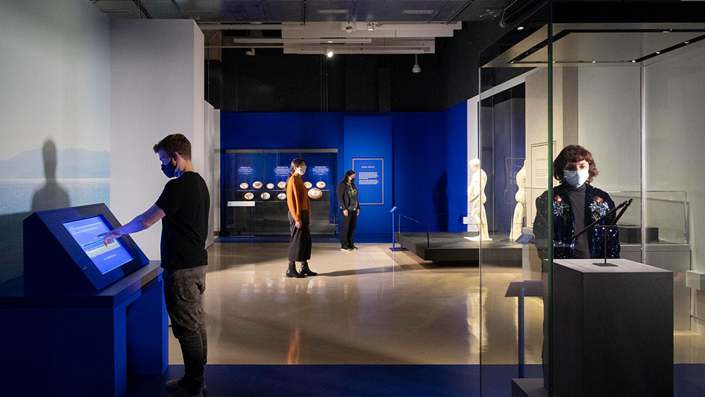 Τέσσερα άτομα διάσπαρτα στον χώρο του μουσείου με αρχαία ελληνικά εκθέματα 