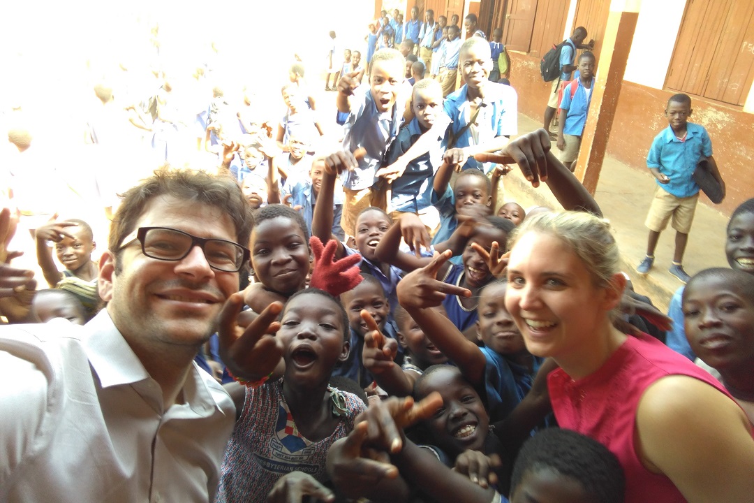 Δύο μέλη του Ιδρύματος Σταύρος Νιάρχος φωτογραφίζονται με πολλά χαμογελαστά παιδιά στη Γκάνα