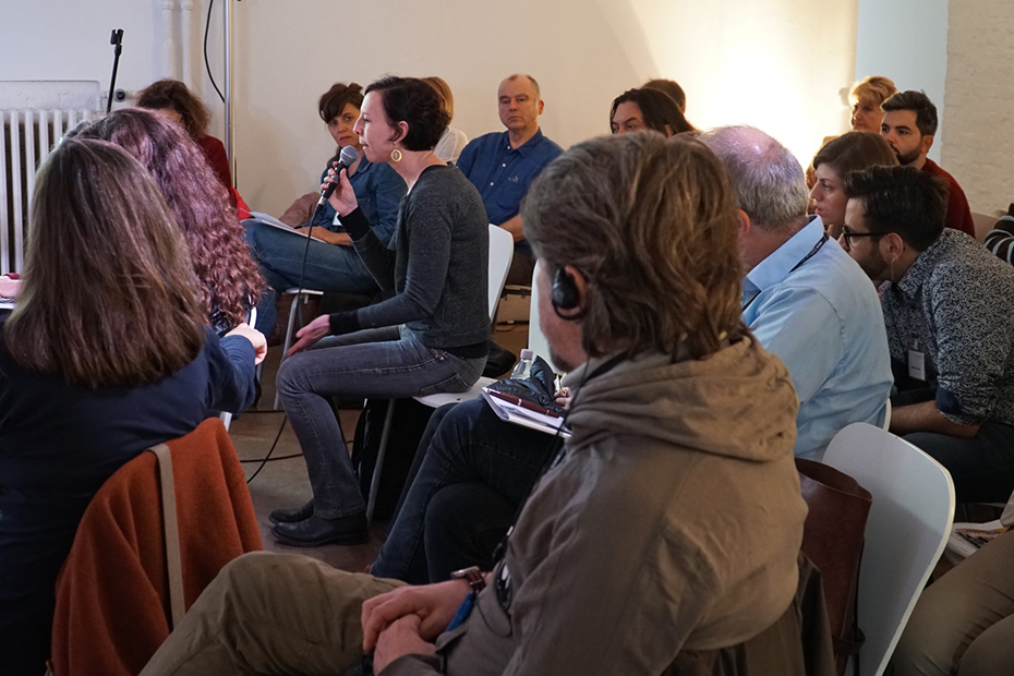 Μια γυναίκα που ανήκει στο καθισμένο κοινό κάνει ένα σχόλιο στο μικρόφωνο