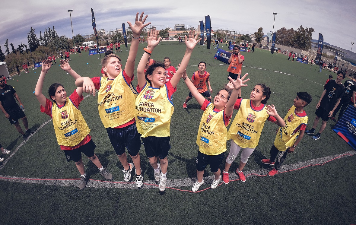 Μερικά παιδιά σηκώνουν τα χέρια τους και πηδούν για να πιάσουν μια μπάλα