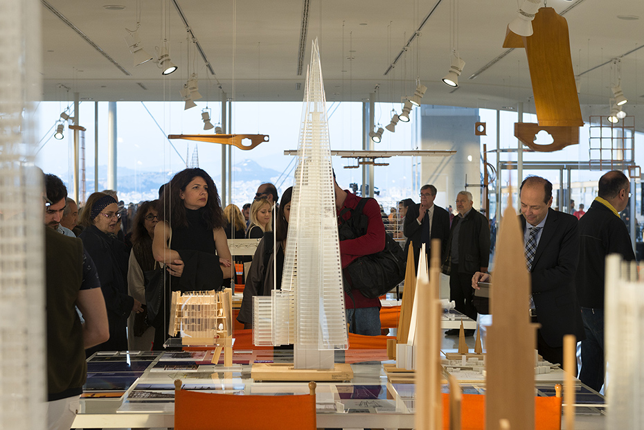 Κοντινή φωτογραφία από ένα τραπέζι στο οποίο φαίνεται μια μεγάλη μακέτα ενός ψηλού κτηρίου 