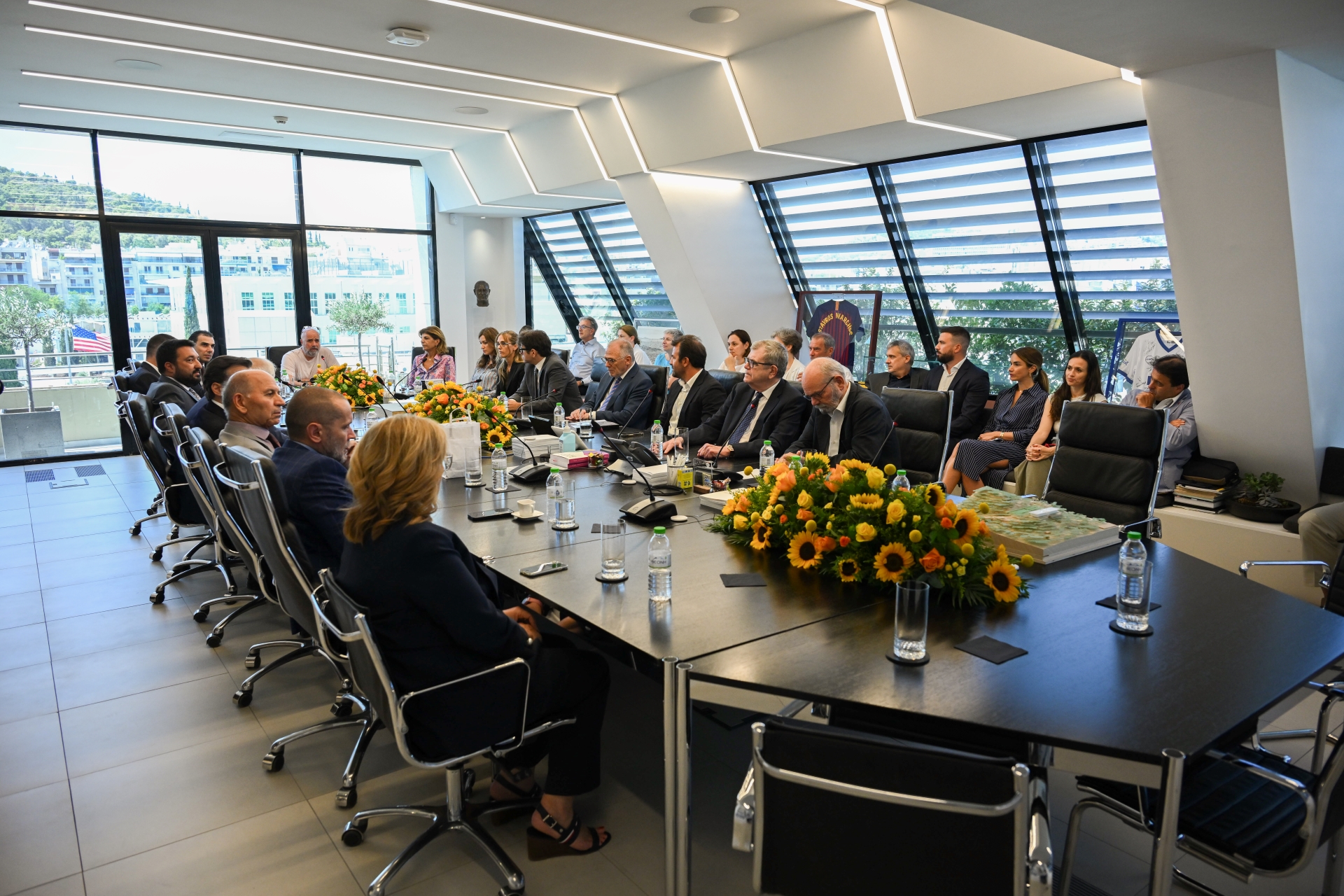 Πολλά μέλη και συνεργάτες του Ιδρύματος Σταύρος Νιάρχος, κάθονται γύρω από ένα τραπέζι και συζητούν 