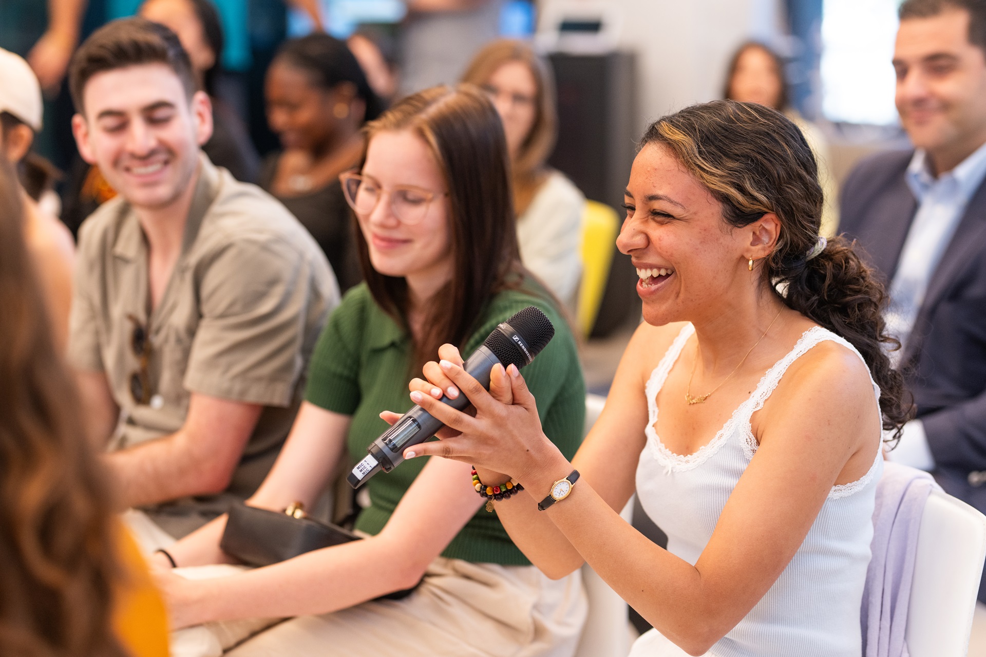 Ένα κορίτσι κρατά το μικρόφωνο ενώ γελά και μιλά στην συζήτηση που έγινε στο ΙΣΝ.