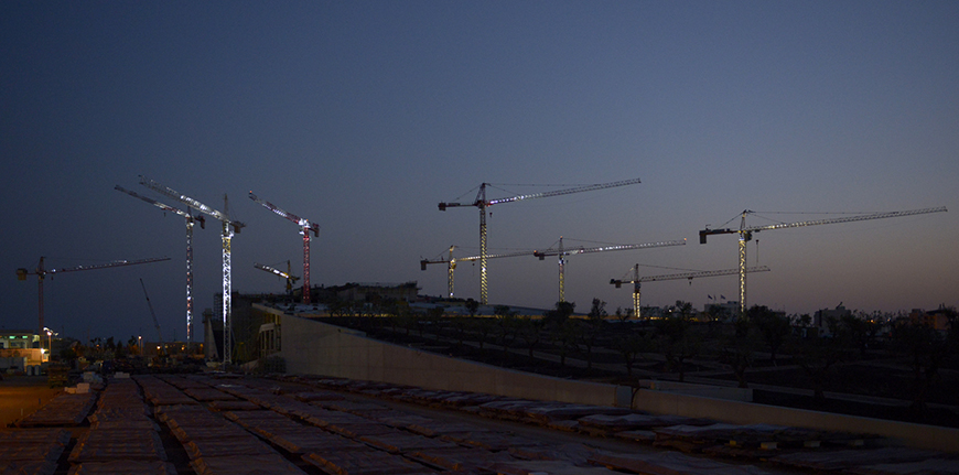 Μακρινή φωτογραφία που δείχνει γερανούς τοποθετημένους μέσα σε ένα εργοτάξιο