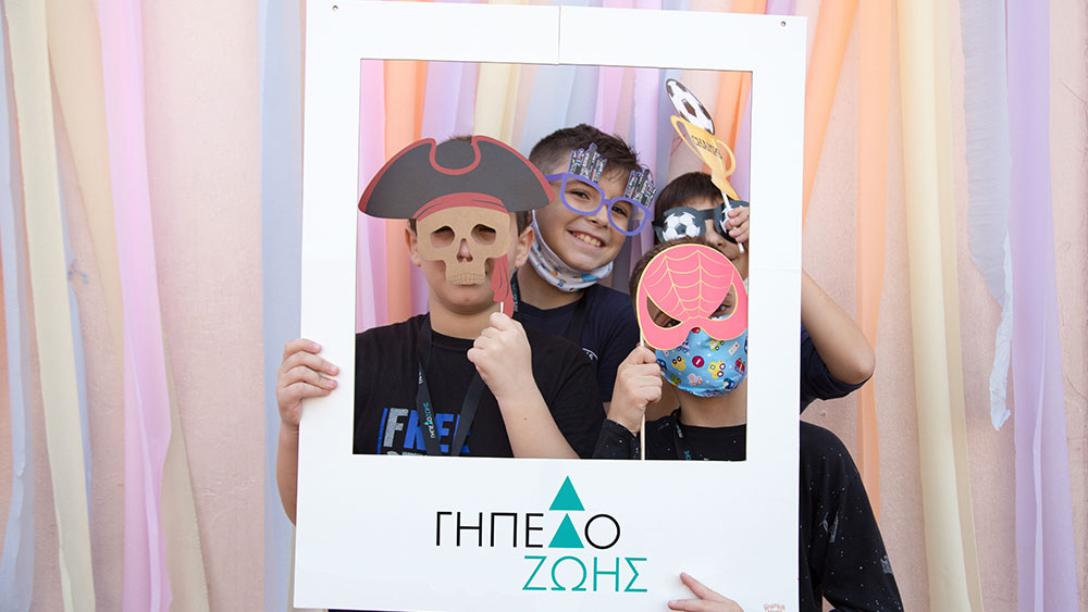 Τέσσερα μικρά αγόρια φοράνε αποκριάτικες μάσκες και κρατάνε ένα πλαίσιο που γράφει 